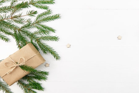 Christmas composition with fir tree branches and gift box on white wooden background. Winter...