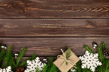 Winter holidays background with fir tree branches, gift box and snowflakes on wooden background....