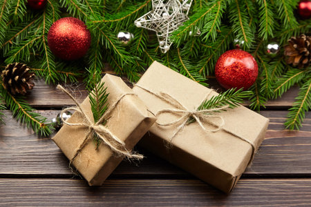 Christmas gift boxes with decorated fir tree branches on dark wooden background. Festive New Year...