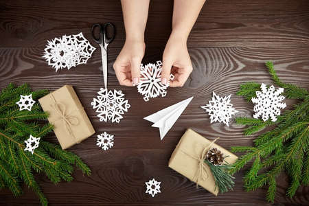 Hands holding white paper snowflake over wooden tableの写真素材
