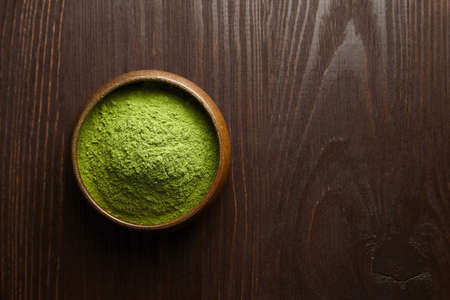 Wheatgrass or barley grass powder in wooden bowl on dark background. Detox superfood. Top view, copy space.の写真素材