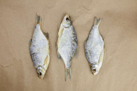 Three dry fish on parchment paper background, beer snack, top view.の写真素材