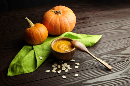 Bowl with pumpkin soup and fresh pumpkins on dark rustic wooden table background.の写真素材