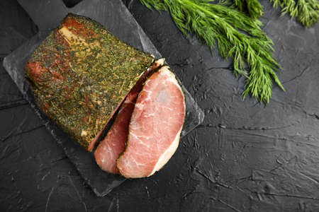 Dried pork, polendwitz, jerky tenderloin, fresh green dill, slate cutting board on black background, top view. Cured pork meat. Polenitsa is a dry-cured filet. Dish of Belarusian cuisineの写真素材