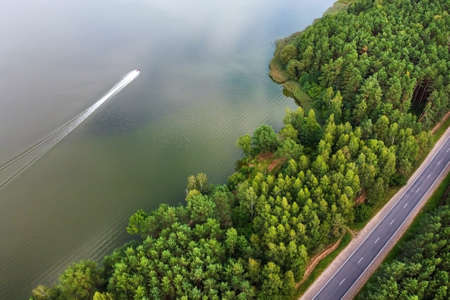 Aerial view of summer landscape with road, pine forest and river with water scooterの写真素材