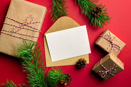 Christmas greeting card mockup. Gift boxes, pine tree branches with cones on red paper background....