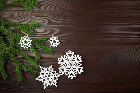 Christmas composition with white paper snowflakes and fir tree branch on wooden backgroundの写真素材