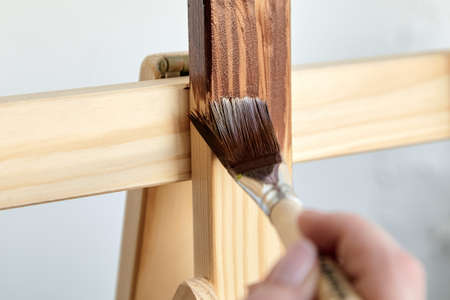 Varnish coating. Protective acrylic coating of wooden surface. Wood Finishing. Paintwork. A synthetic paint brush, board, brown color varnishの写真素材