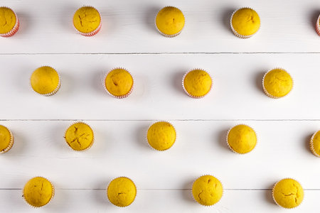 Muffins on white table, flat lay. Rows of cupcakes on wooden background, top view. Homemade bakery, muffin patternの写真素材