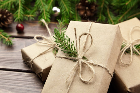 Christmas and New Year gift boxes with fir tree branches, cones and berries on wooden background