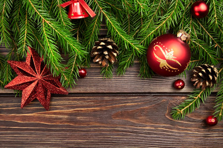Christmas and New Year composition with fir tree branches and red christmas decorations with cones on wooden background, top view.の写真素材