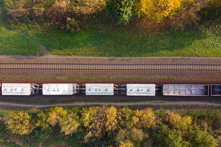 Aerial view of cargo train, a double-track railway in countryside. Railroad with green grass and...
