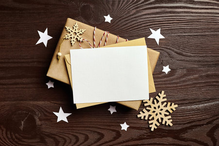Christmas greeting card mockup with gift box and wooden decorations on wooden background, flat lay,...
