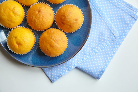 Pumpkin muffins on blue plate on white table, top view. Homemade bakery, plant-based food, vegetable...