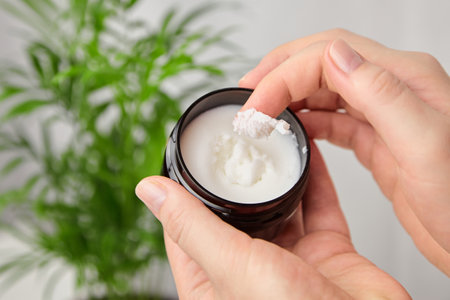 Female hand applying pure shea butter. Anti-aging treatment. Skin and hair care moisturizing product, natural cosmetics.の写真素材