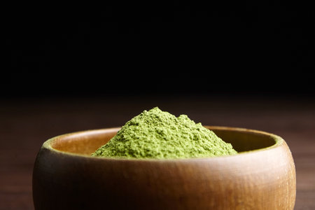 Wheatgrass organic powder heap in wooden bowl on dark table background, closeup, copy space.の写真素材