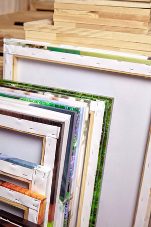 ? anvas prints, stack of colorful photos with gallery wrapping method of canvas stretching on wooden...
