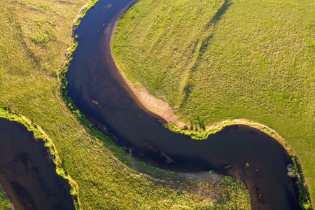 Aerial view of winding river. Summer landscape, top view. A green valley with a winding riverbed and...