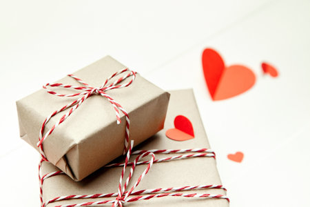 Valentines day gift box and red paper hearts on white wooden backgroundの写真素材