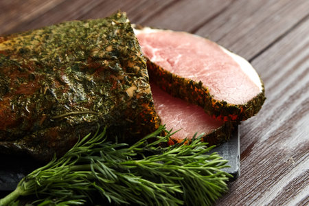 Polendwitz is a jerky tenderloin, dried pork with spices and fresh green dill, slate cutting board on brown table. Cured filet, pork jerky on wooden backgroundの写真素材
