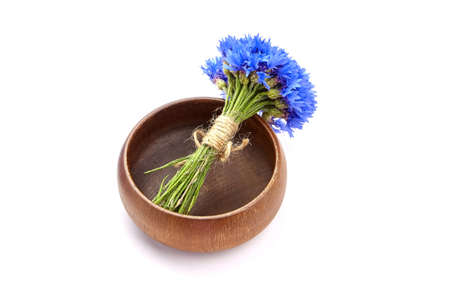 Fresh blue cornflowers bouquet in empty wooden bowl isolated on white backgroundの写真素材