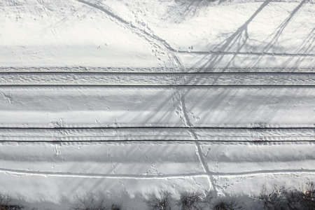 Aerial view of a double-track railway after heavy snowfall. Winter rail road with white snow, top view. Transport infrastructure, train track, snowy landscapeの写真素材