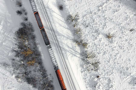Aerial view of cargo train wagons, a double-track railway. Winter rail road with white snow, top view. Transport infrastructure, train track, snowy landscapeの写真素材