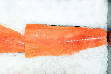 Salmon trim on white ice background, top view. Fresh raw salmon fish fillet in fish marketの写真素材
