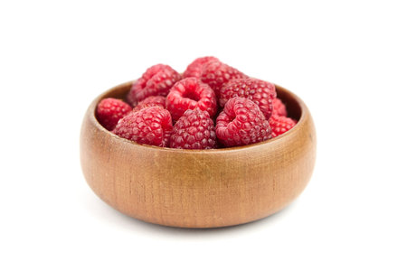 Fresh raspberries in wooden bowl isolated on white background. Red ripe raspberries, sweet summer...