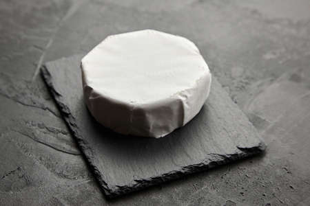 Camembert cheese on black slate board over dark concrete background, italian food conceptの写真素材