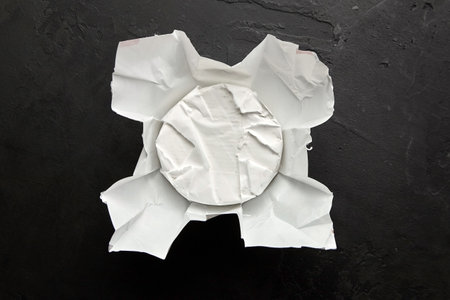 Camembert cheese in packaging paper on dark slate background, top viewの写真素材