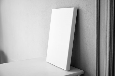 White canvas mockup, blank picture on white wooden table in interior with gray wall