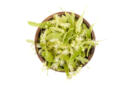 Linden flowers in wooden bowl isolated on white background, top view