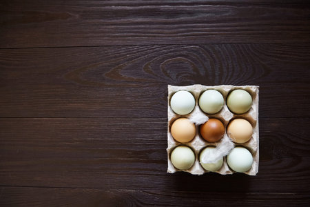 Chicken eggs in tray on wooden table. Nine eggs in cardboard holder on brown table
