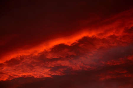 Red sunset sky with dramatic clouds. Scenic clouds illuminated by red sunlightの写真素材