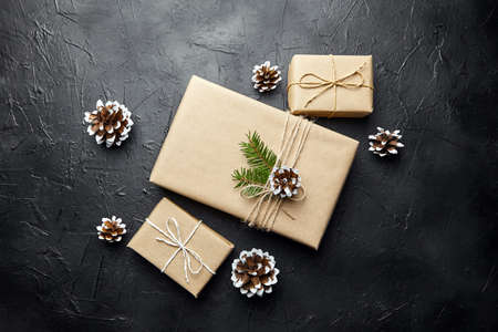 Gift boxes and green Christmas tree branch with cone on dark background top viewの写真素材