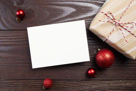 Christmas or New Year greeting card mockup with gift box and red balls decorations