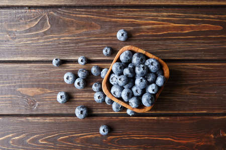 Bowl with fresh blueberries on brown wooden table top viewの写真素材