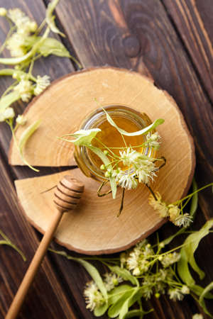 Dipper and honey jar with fresh linden blossom on wooden table top viewの写真素材
