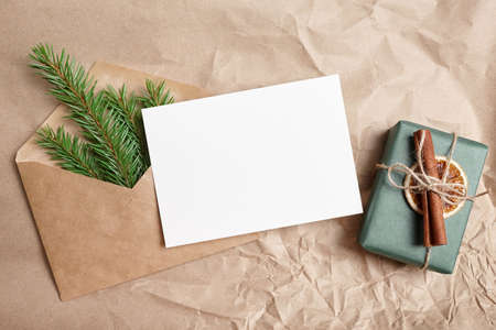 Christmas greeting card mockup with decorated gift box and envelope with green fir tree branchの写真素材