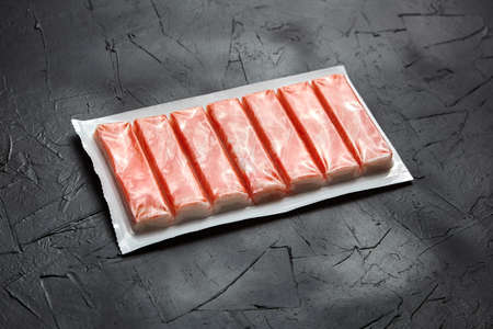 Crab sticks or imitation crab meat surimi in a package on black tableの写真素材