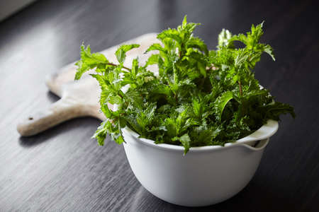 Fresh mint leaves in white bowl on wooden table. Green speamint bunchの写真素材
