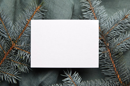 Christmas greeting card mockup with fir tree branches on green cloth background, top view, flat layの写真素材