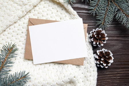 Christmas greeting card mockup with envelope, knitted sweater, green fir tree branches and cone on...