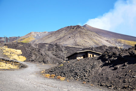 Volcano Etna, Sicily, Italy. Black slopes with road and cableway. Crater of Etna. Smoking peak of active volcano Etna.の写真素材