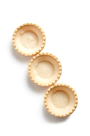 Tartlet shells isolated on white background, top view. Three empty crispy mini tart shells for portable dessertsの写真素材