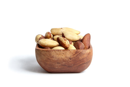 Brazil nuts in wooden bowl isolated on a white background. Exotic Brazil nuts, a taste of Brazilの写真素材