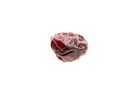 Close-up of a solitary dried cranberry, presented on a pristine white surfaceの写真素材