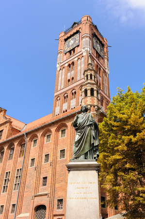 TORUN, POLAND - JULY 7, 2009: Monument of Nicolaus Copernicus holding an astrolabe in front of the old town hall and tower on a granite pedestal bearing a Latin inscription in gold lettersのeditorial素材
