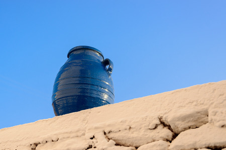 Belly amphora painted blue on a limewashed stone wall at a Greek Cyclades Islandの写真素材